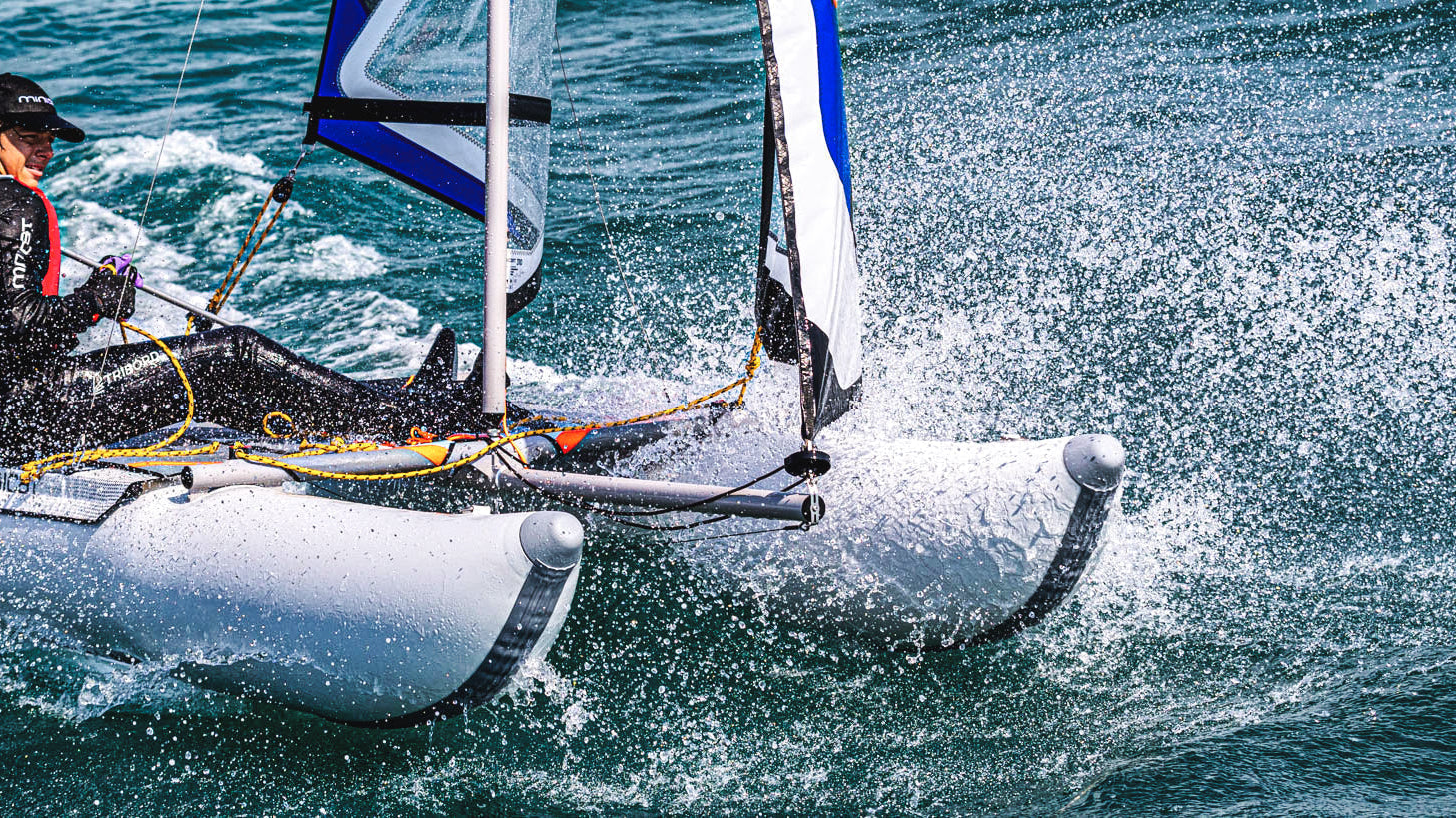 MiniCat model 310 Sport with blue sails sailing fast on the sea with a young boy sailing it