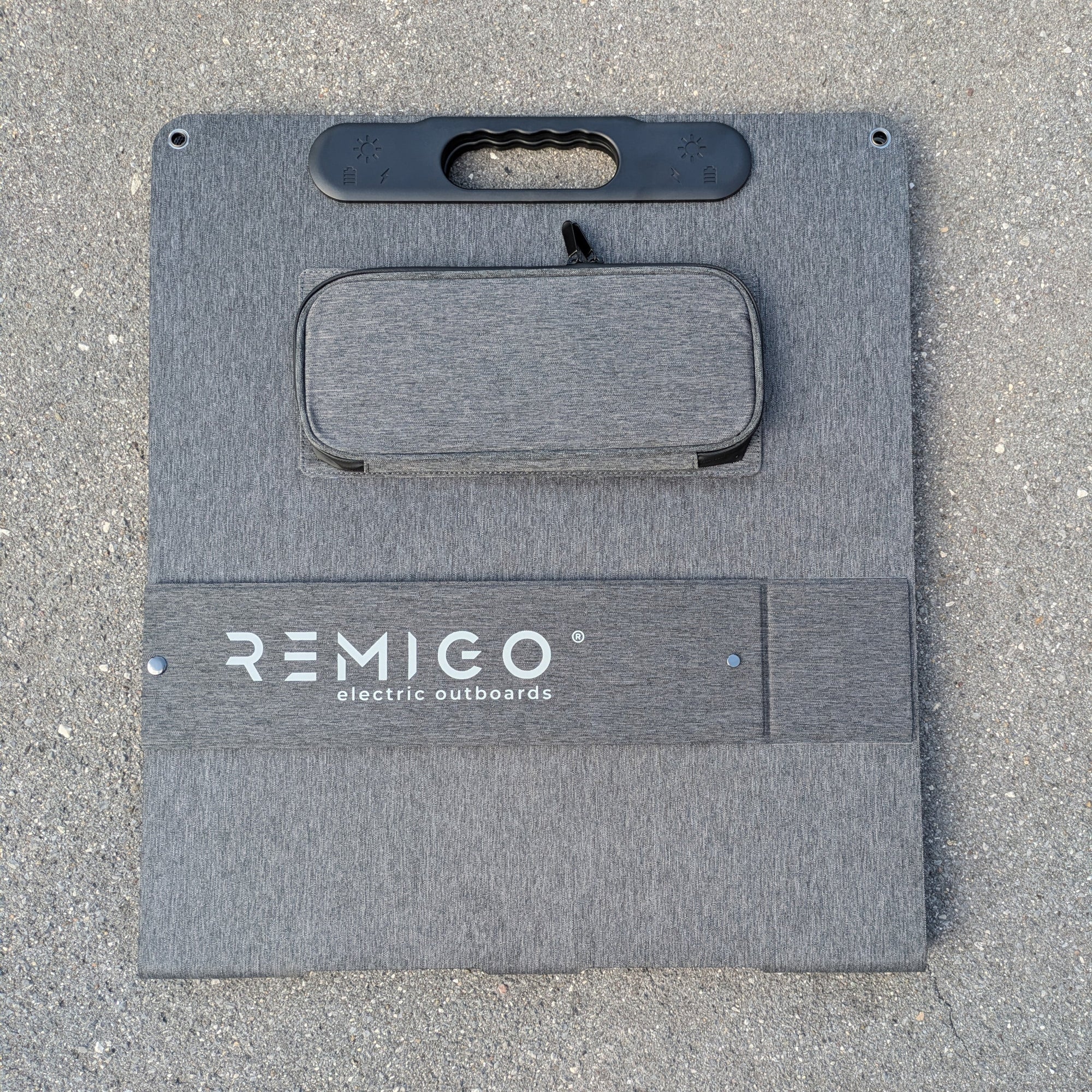 Gray solar panels cover with 'REMIGO' branding on a concrete surface