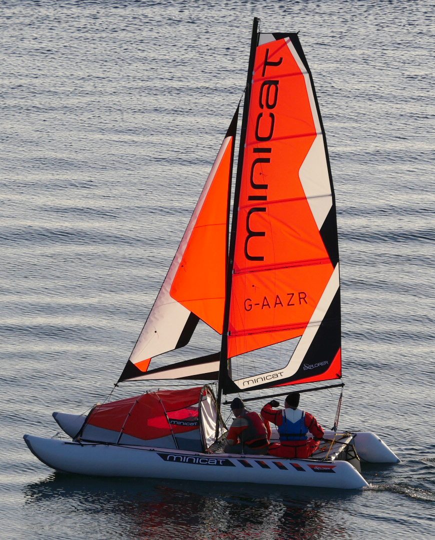 Minicat 520 Explorer sailboat with an orange sail on a body of water