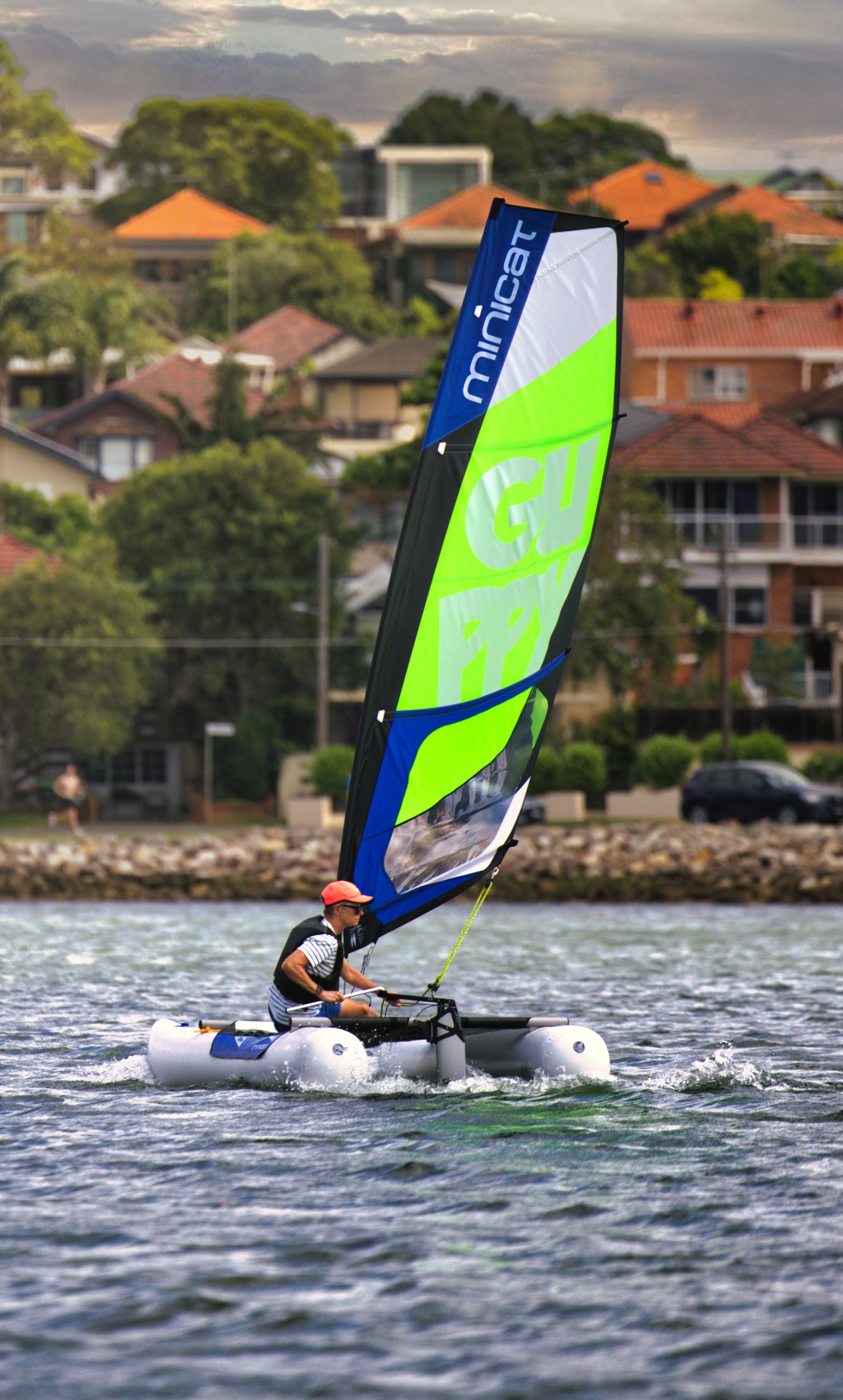 Person sailing MiniCat on the water with residential buildings in the background