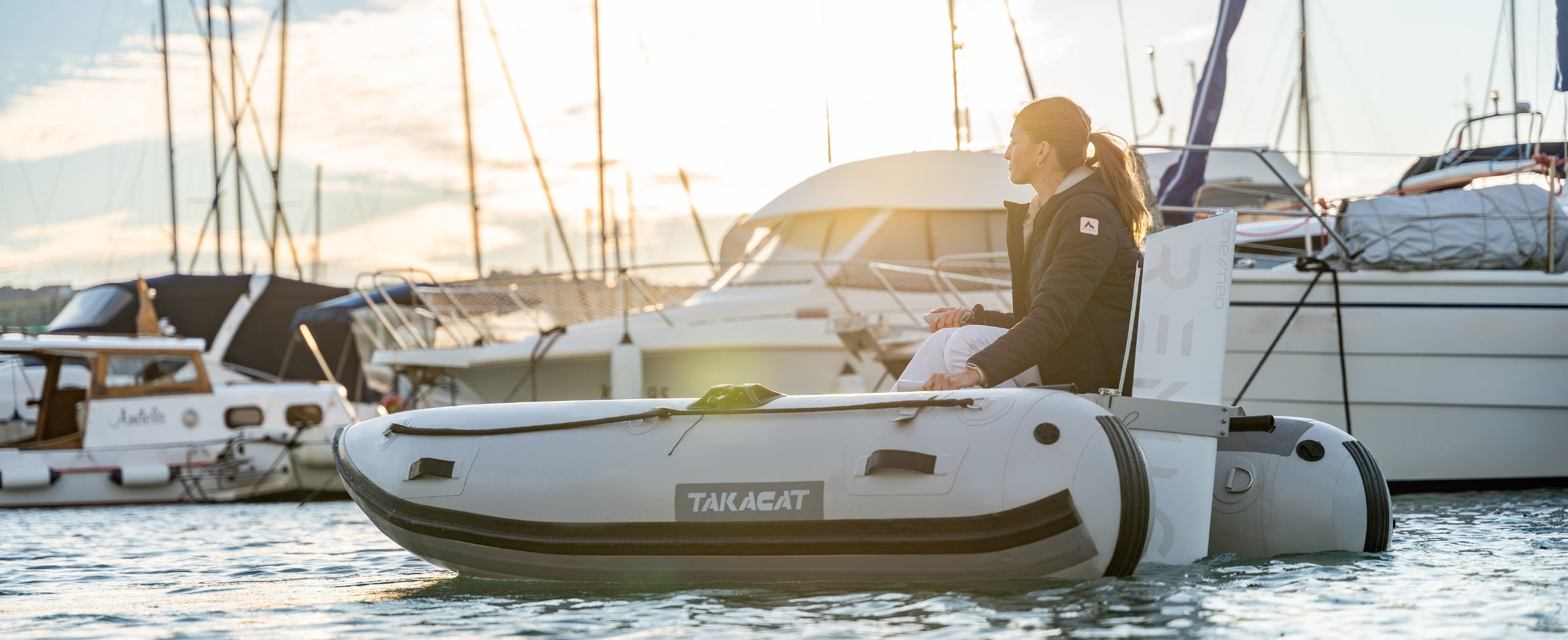Person on a Takacat inflatable boat with Remigo engine with yachts in the background