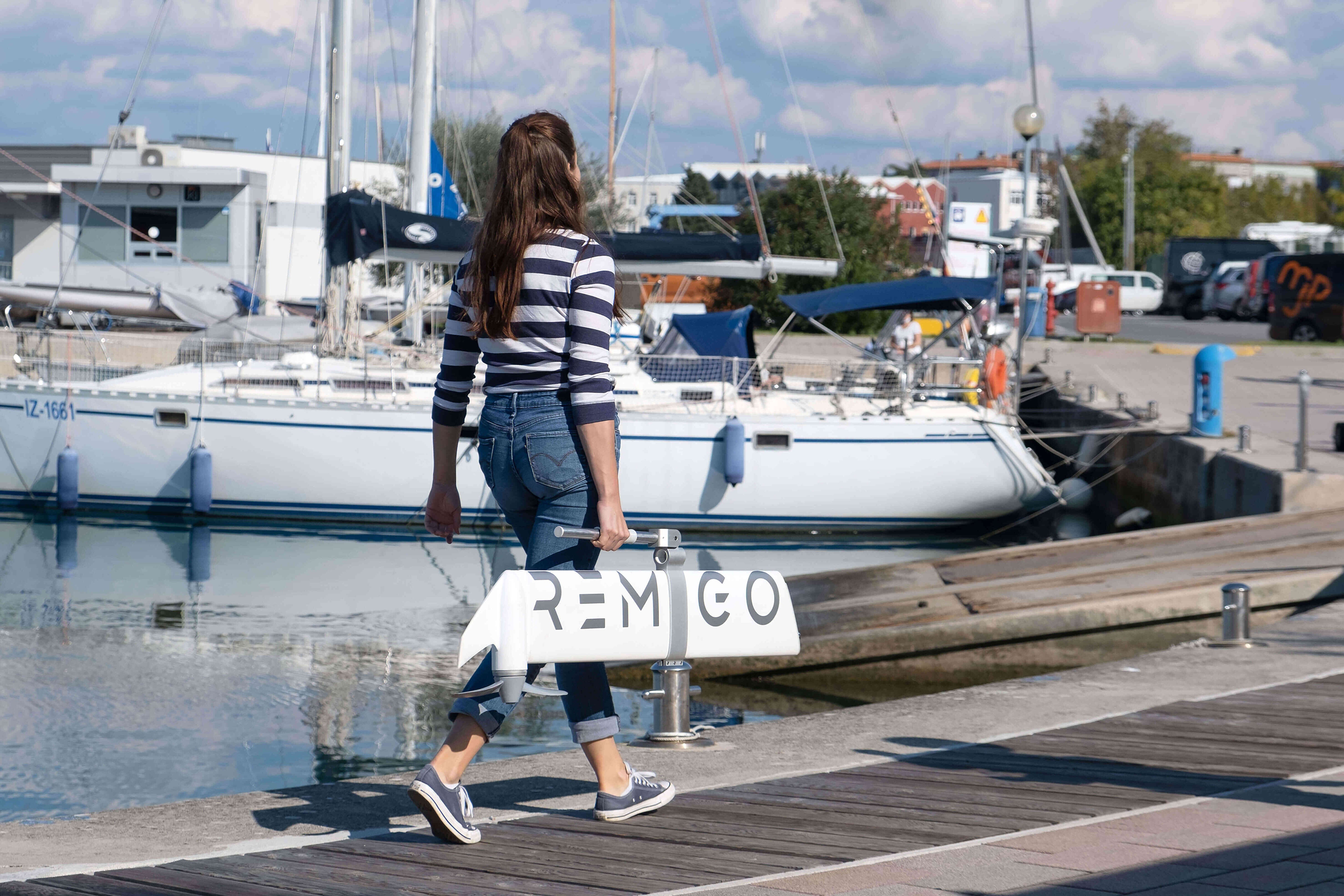 Woman walking on a dock with boats in the background