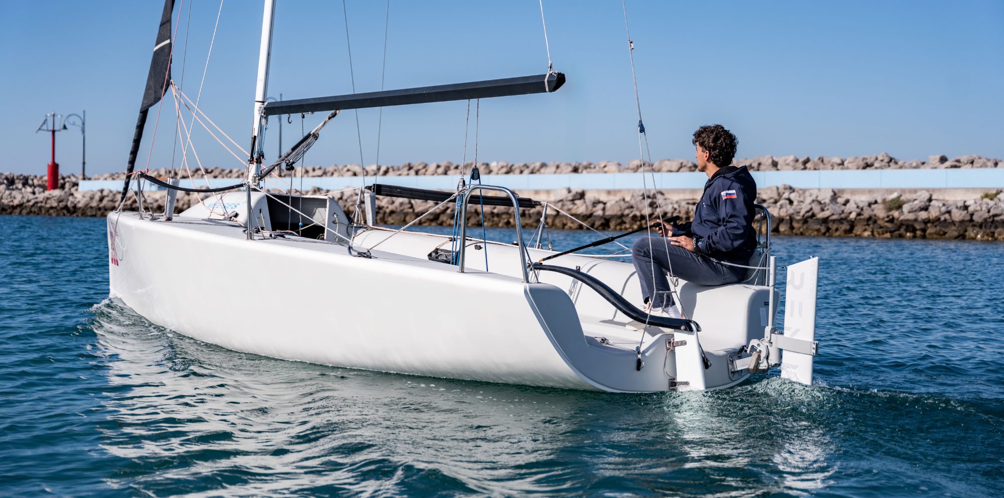 Person on a sailboat with Remigo in the water with a clear sky