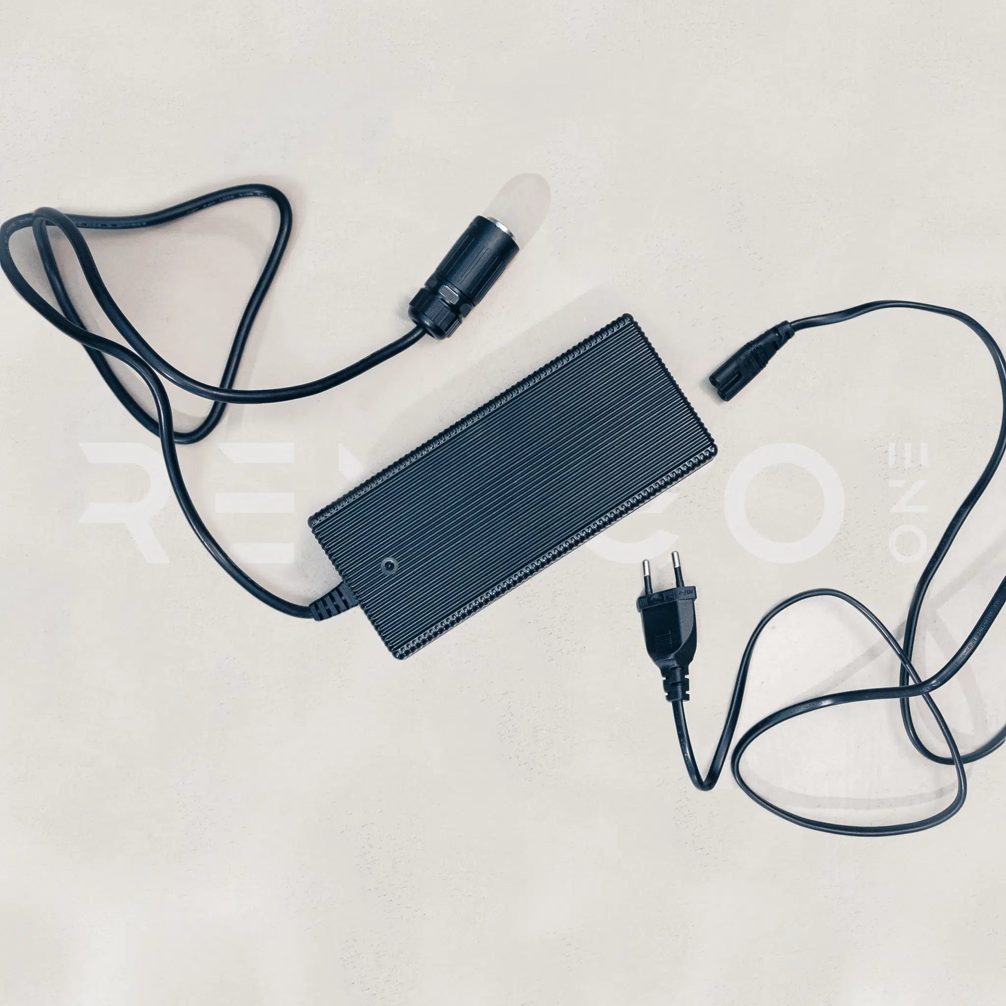 Black power adapter with cables on a light gray background
