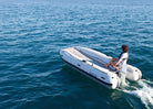 Person on a white inflatable boat in the ocean holding Remigo electric engine